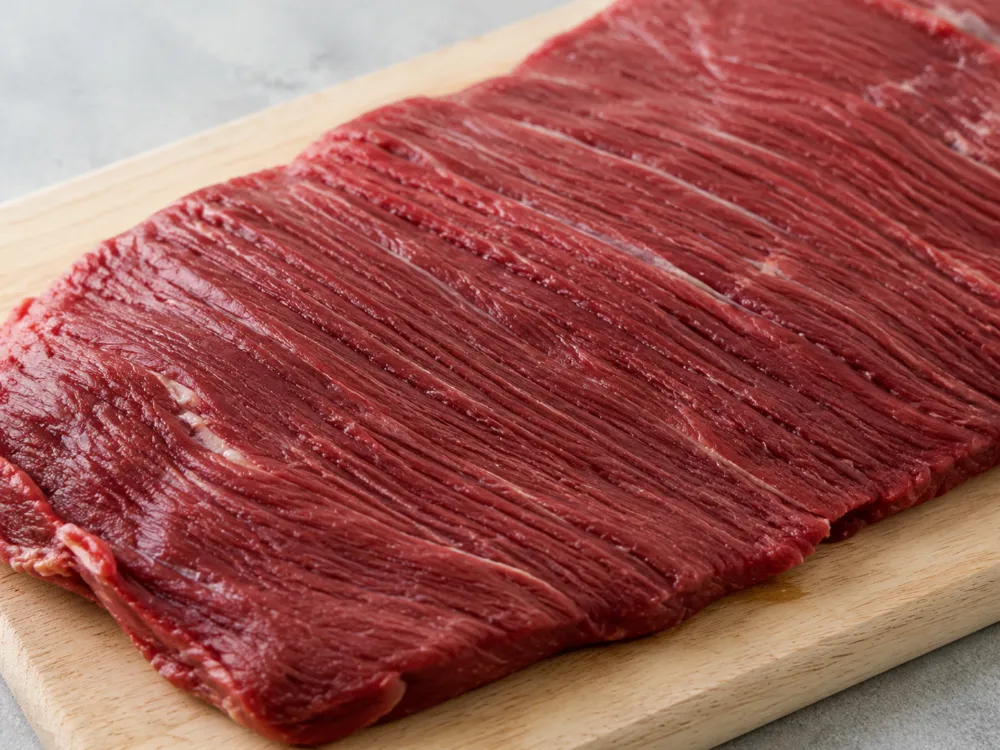 Surowy flank steak z bliska: długie, równoległe włókna i prawie brak marmurku